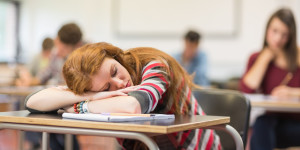 Blurred students in the classroom with one asleep girl